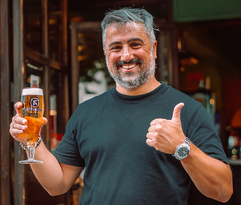 titolare del pub Lowen Inn con birra in mano e sorridente